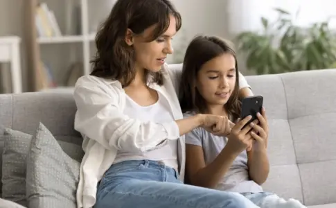 Mutter und Tochter nutzen gemeinsam Smartphone im digitalen Alltag zu Hause
