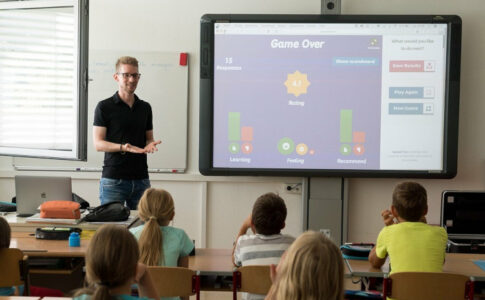 Ein Lehrer steht vor einem Smartboard und unterrichtet