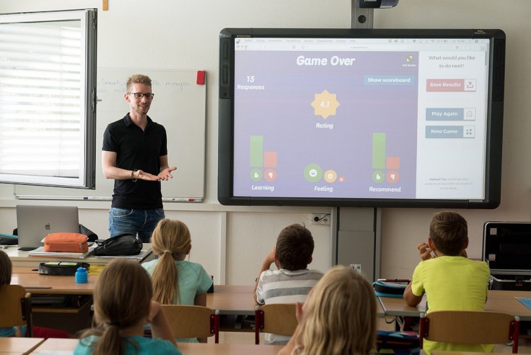 Ein Lehrer steht vor einem Smartboard und unterrichtet