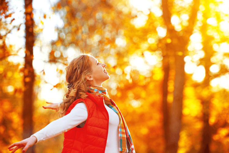 Glückliche Frau genießt die herbstlichen Farben des Waldes