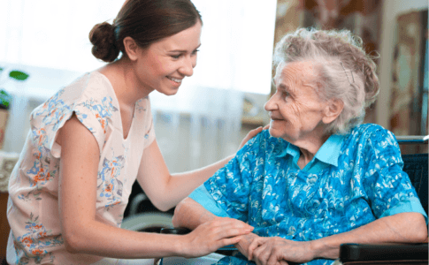 Eine junge Frau kümmert sich um eine ältere Frau im Rollstuhl
