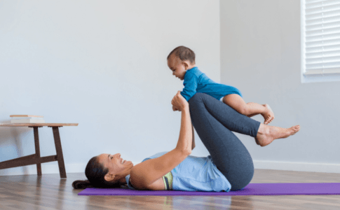 Mutter mit ihrem Baby auf einer Yoga-Matte beim Sport