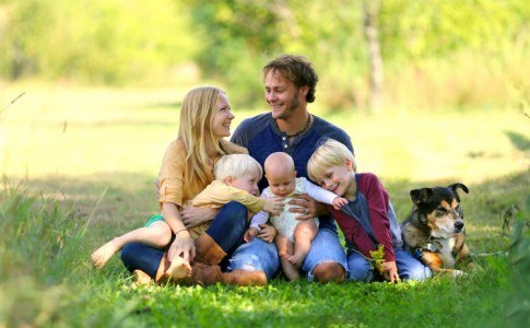 Glückliche Familie sitz mit ihrem Haustier im Grünen