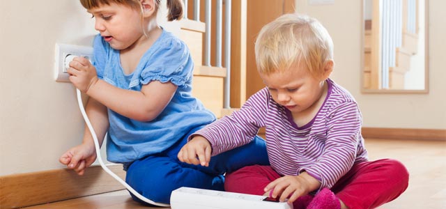 Kinder spielen mit Steckdose