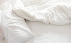 Weiße Bettwäsche liegt auf einer Matratze