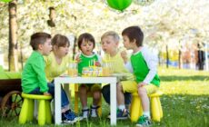 Fünf Kinder sitzen im Garten an einem Tisch. Es wird Geburtstag gefeiert.