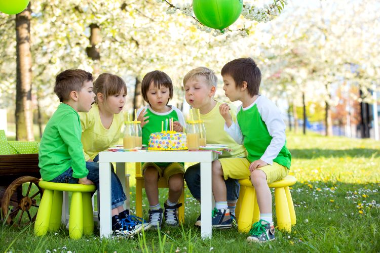 Fünf Kinder sitzen im Garten an einem Tisch. Es wird Geburtstag gefeiert.