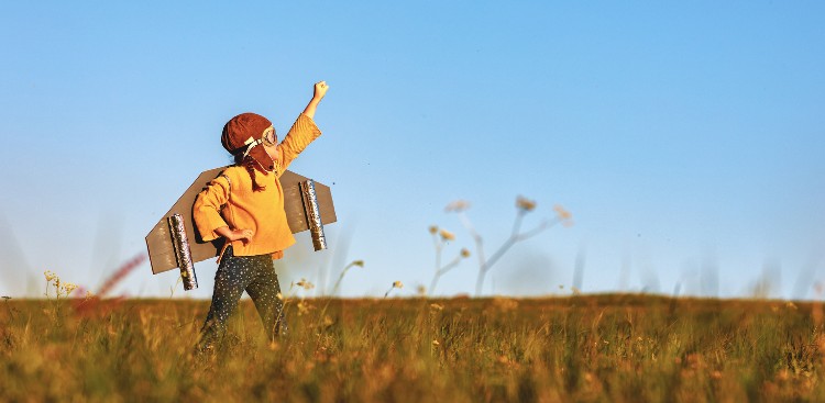 Ein Kind steht im Feld und ist als Pilot verkleidet