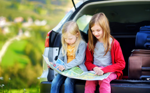 Zwei Kinder im Auto die auf eine Karte schauen