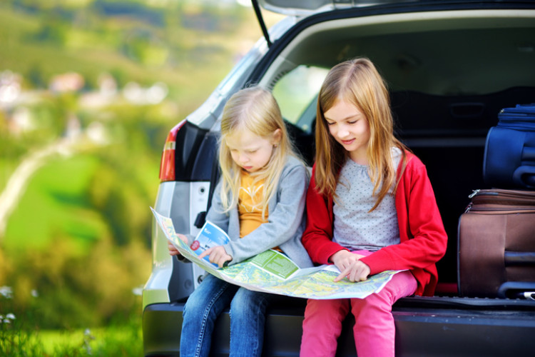 Zwei Kinder im Auto die auf eine Karte schauen