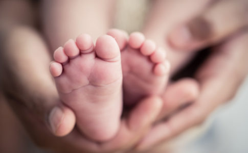 Baby Füße auf der Hand eines Elternteils
