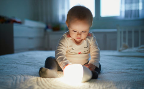 Kleines Baby welches eine Lampe hält