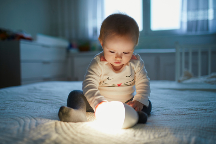 Kleines Baby welches eine Lampe hält