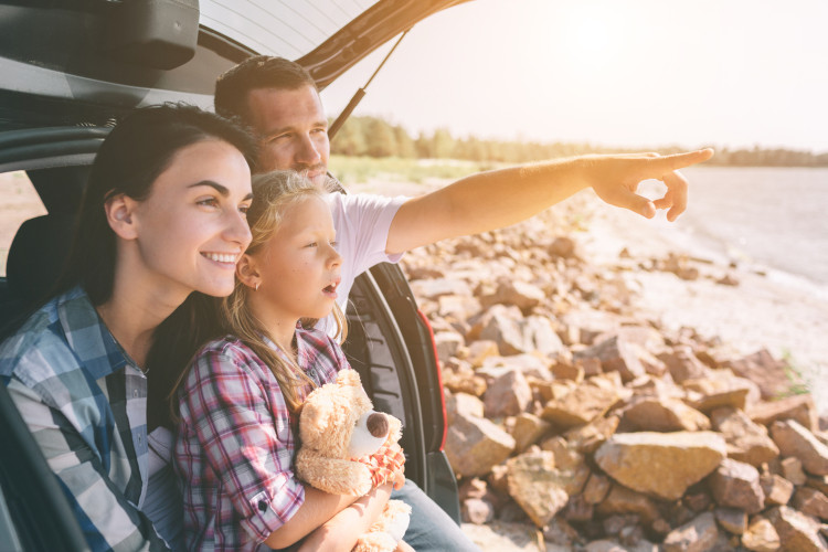 Familie sitzt im Kofferraum bei gutem Wetter