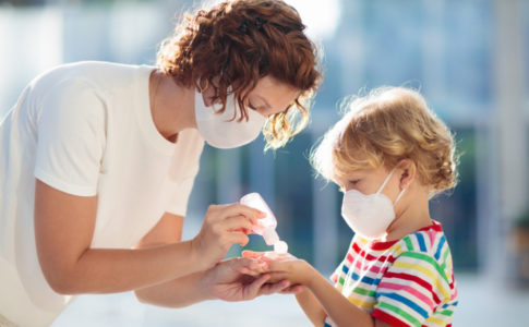 Mutter Kind mit Maske und Desinfektionsmittel