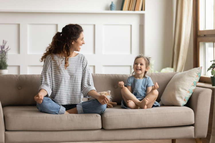 Mutter und Tochter meditieren auf dem Sofa