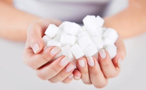 Frau hält Zuckerwürfel in der Hand