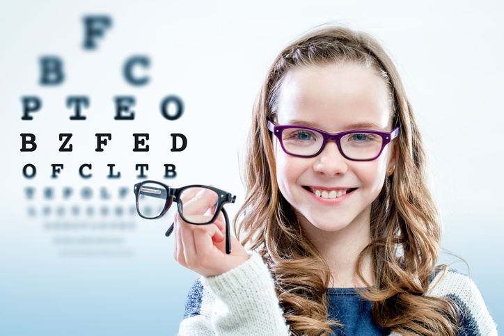 Kind hält Brille vor Sehtesttafel