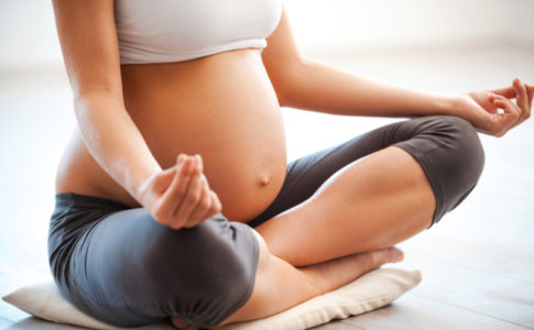 Schwangere Frau die im Yoga Sitz sitzt