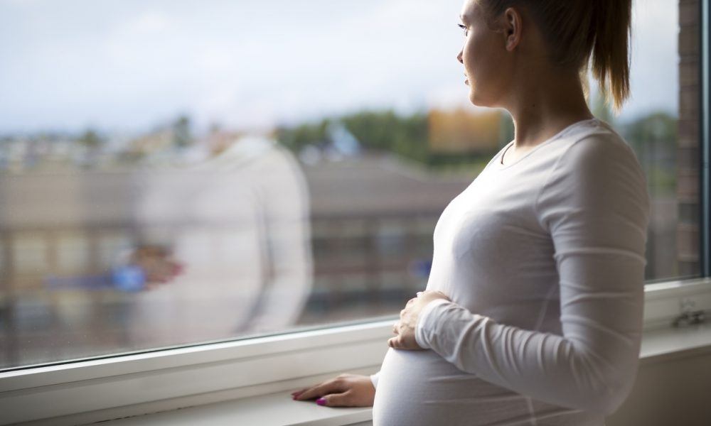 Schwangere Frau sieht aus dem Fenster