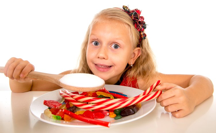 Kind mit einem Teller voll Süßigkeiten vor sich