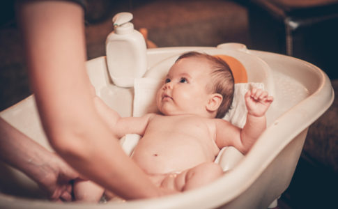 Mutter wäscht ihr Baby in einer Badewanne