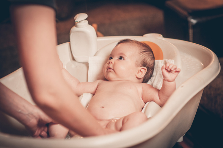 Mutter wäscht ihr Baby in einer Badewanne