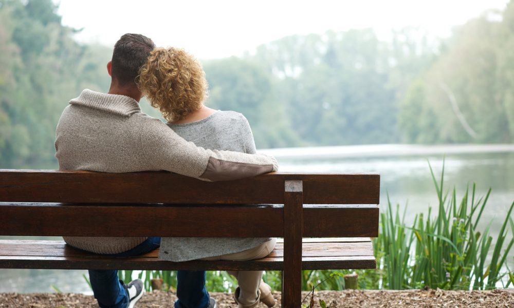 Kinderloses Paar sitzt auf einer Bank am See