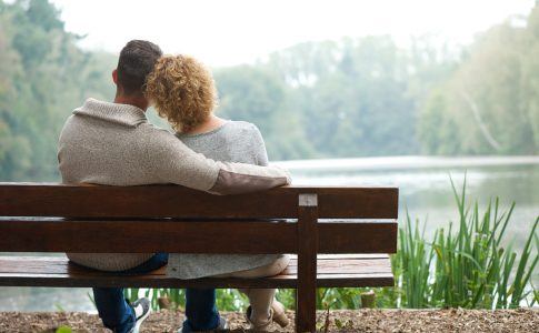 Kinderloses Paar sitzt auf einer Bank am See