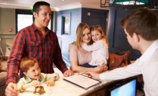 Family Checking In At Hotel Reception Desk