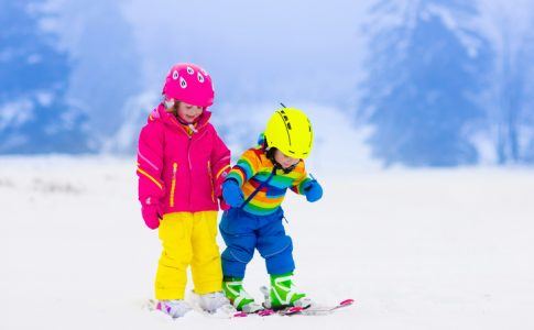 Zwei Kinder üben Ski fahren im Schnee