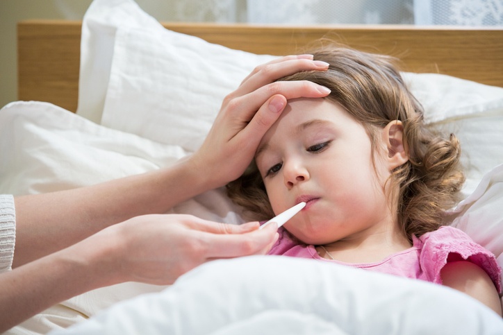 Krankes Kind liegt im Bett mit Fieberthermometer