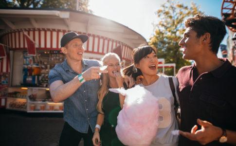 Junge Menschengruppe im Freizeitpark isst Zuckerwatte