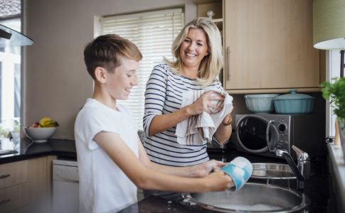 Mutter und Sohn spülen Geschirr