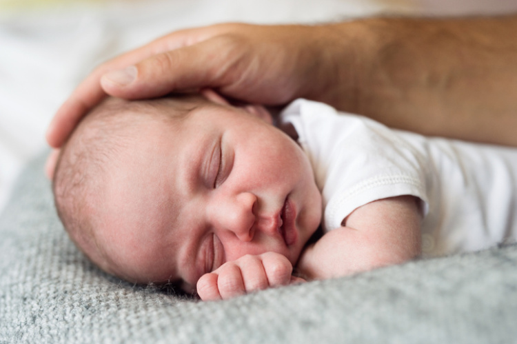 Baby wird am Kopf gestreichelt