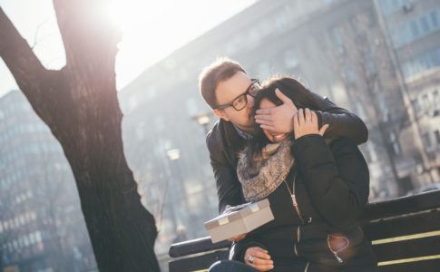 Mann überrascht seine Partnerin mit einem Geschenk im Park