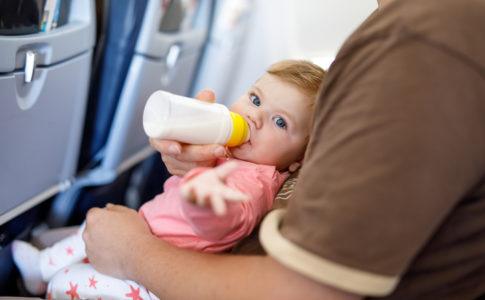 Baby liegt auf Arm im Flugzeug