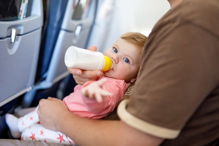 Baby liegt auf Arm im Flugzeug