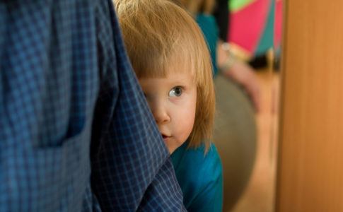 Kind versteckt sich schüchtern hinter Eltern