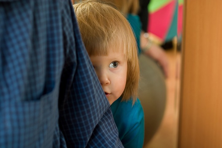 Kind versteckt sich schüchtern hinter Eltern