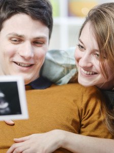 Ein junges Paar schaut sich Ultraschallbilder von ihrem Baby an