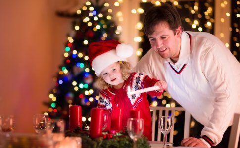 Vater und Tochter entzünden die Kerzen am Adventskranz