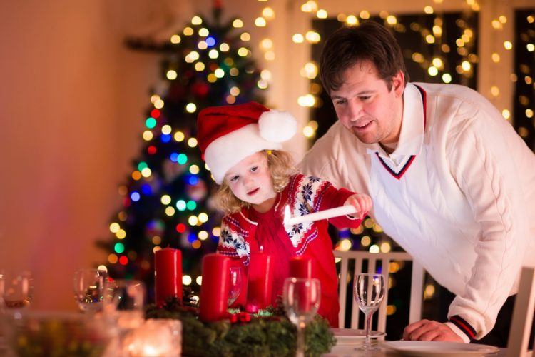 Vater und Tochter entzünden die Kerzen am Adventskranz