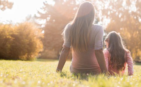 Alleinerziehende Mutter und Kind sitzen auf einer Wiese