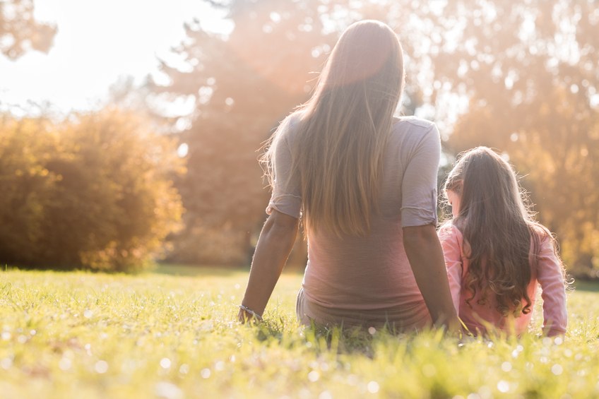 Alleinerziehende Mutter und Kind sitzen auf einer Wiese