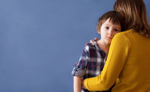 Unterhaltzahlungsbedürftiges Kind schaut über die Schulter der Mutter