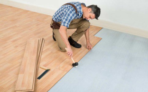Mann verlegt Laminatfußboden in einer hellen Wohnung