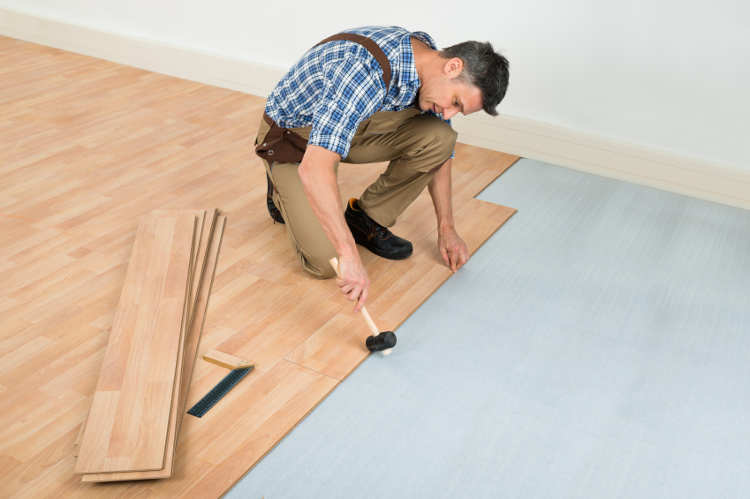 Mann verlegt Laminatfußboden in einer hellen Wohnung