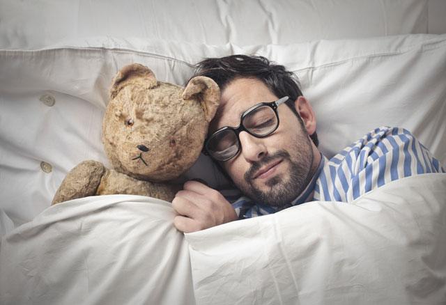 Mann schläft mit Teddy