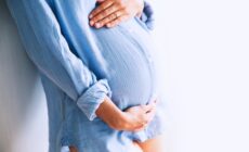 Eine Frau berührt ihren Schwangerschaftsbauch mit der Hand
